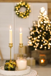 Photo of Burning candles and Christmas gift box on tray indoors