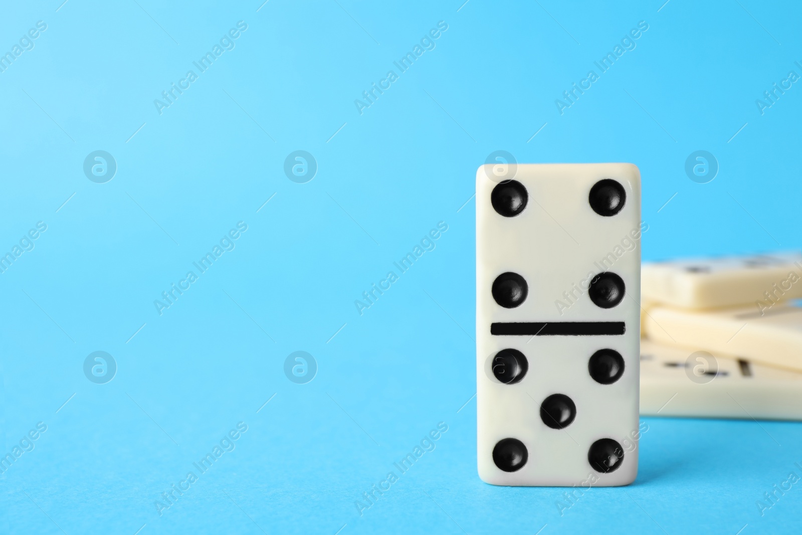 Photo of White domino tiles on turquoise background, closeup. Space for text