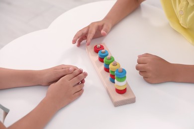 Little children playing with stacking and counting game at desk, closeup. Kindergarten activities for motor skills development