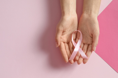 Photo of Woman holding pink ribbon on color background, top view with space for text. Breast cancer awareness