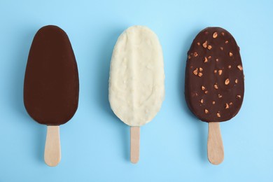 Photo of Glazed ice cream bars on light blue background, flat lay