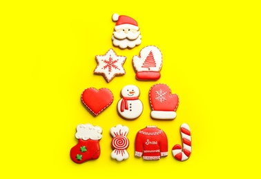 Delicious gingerbread cookies arranged in shape of Christmas tree on yellow background, flat lay