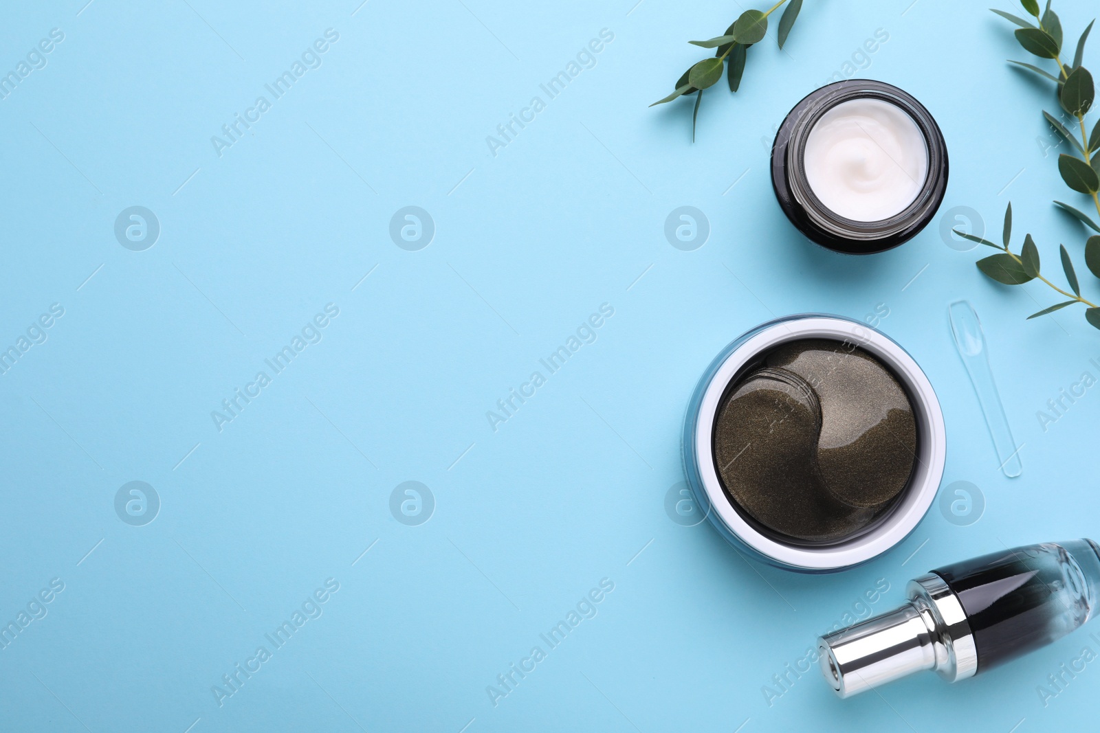 Photo of Flat lay composition with under eye patches and other cosmetic products on light blue background. Space for text