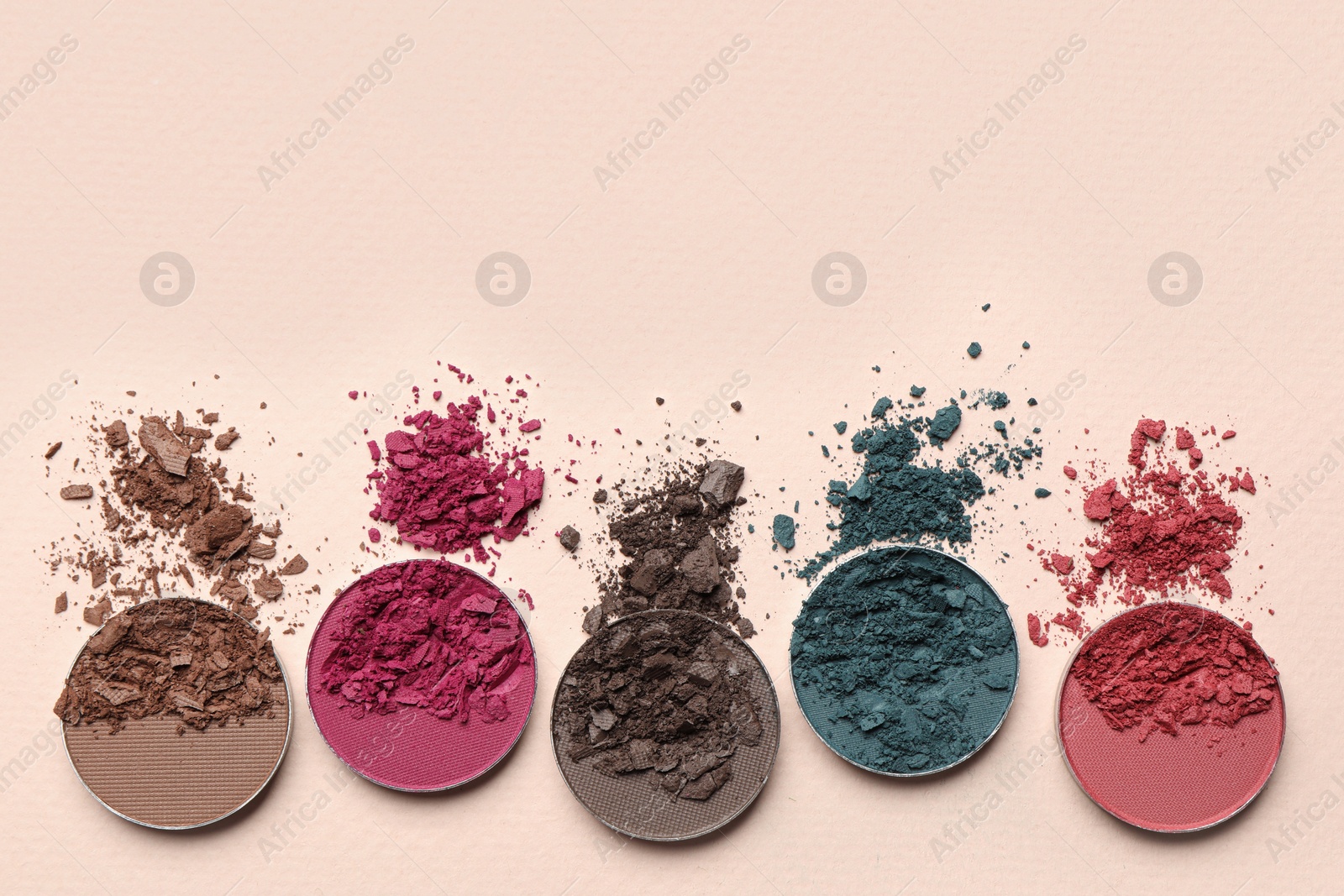 Photo of Different crushed eye shadows on beige background, flat lay. Space for text