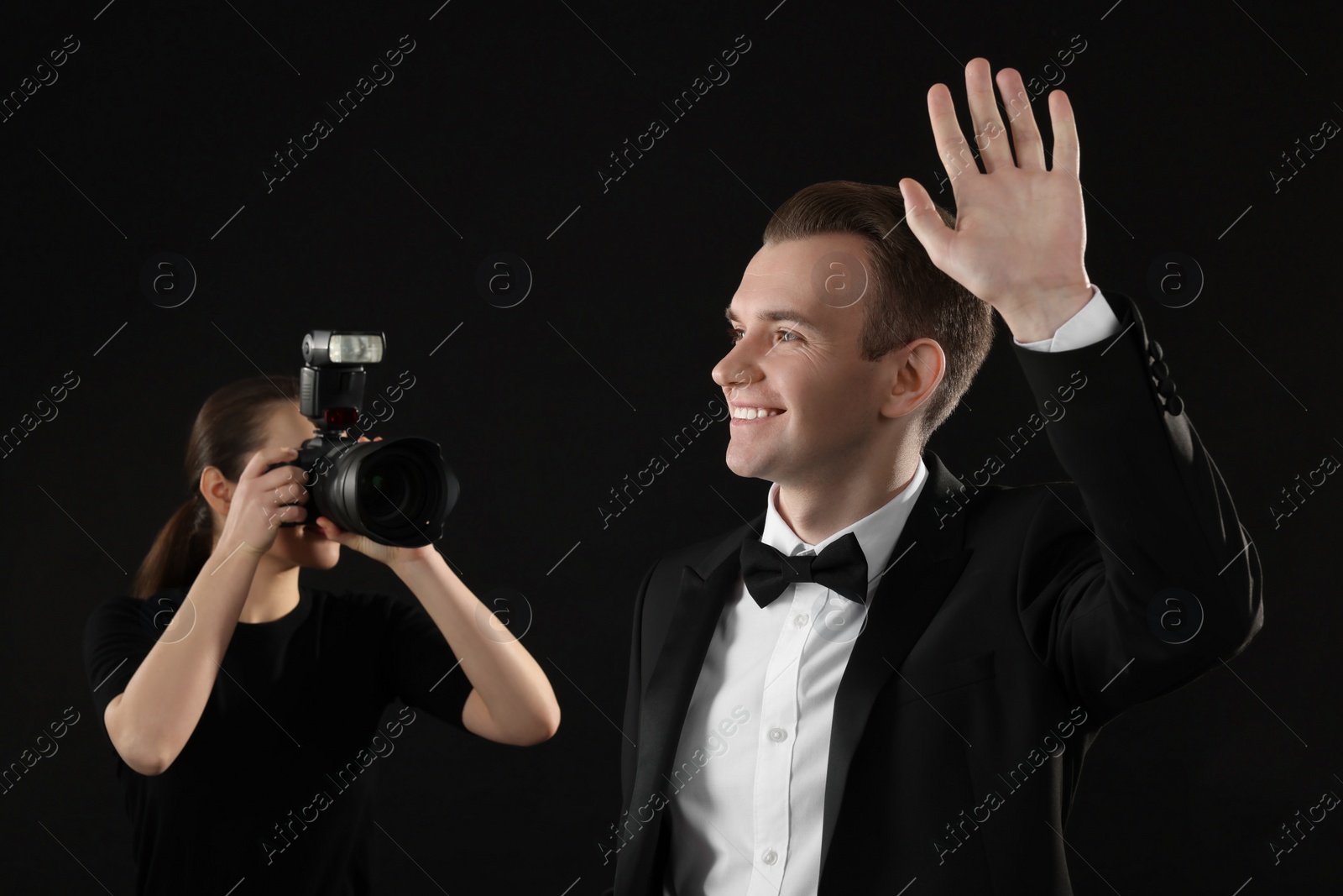 Photo of Professional photographer taking picture of man on black background