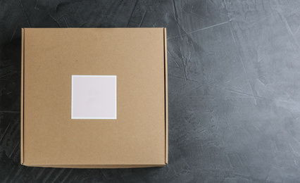 Photo of Closed cardboard box on grey stone table, top view. Space for text