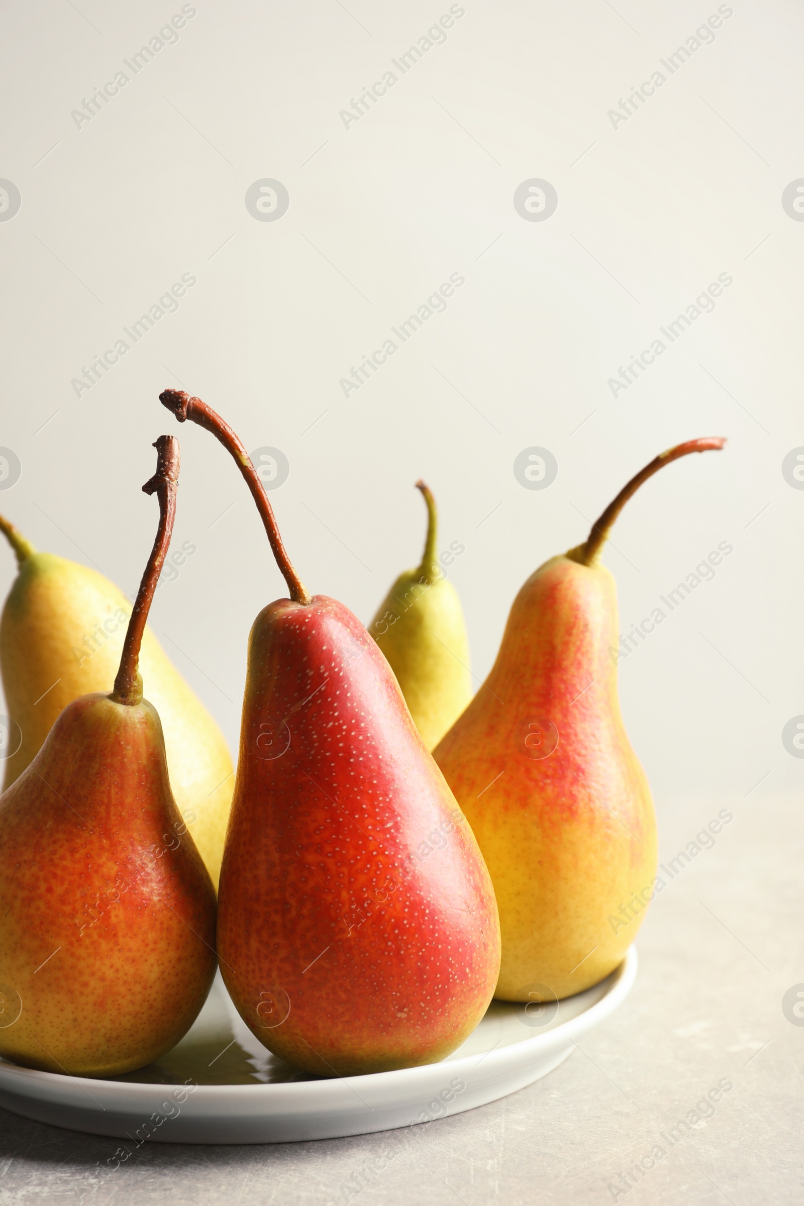 Photo of Plate with ripe pears on light background. Space for text