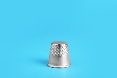 Sewing thimble on light blue background, closeup
