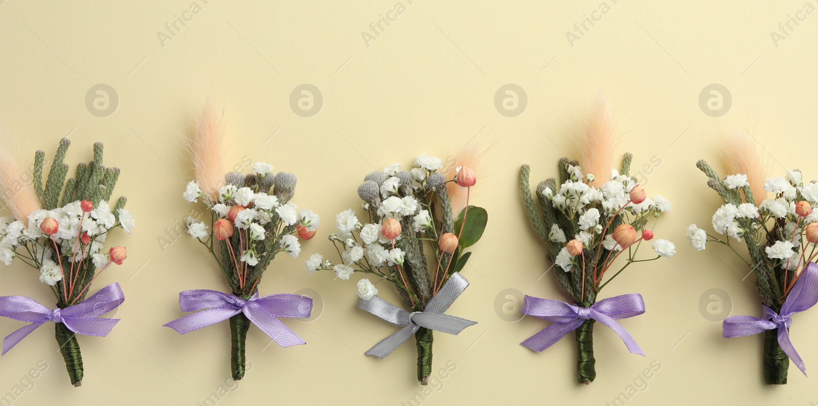 Photo of Many stylish boutonnieres on beige background, flat lay. Banner design