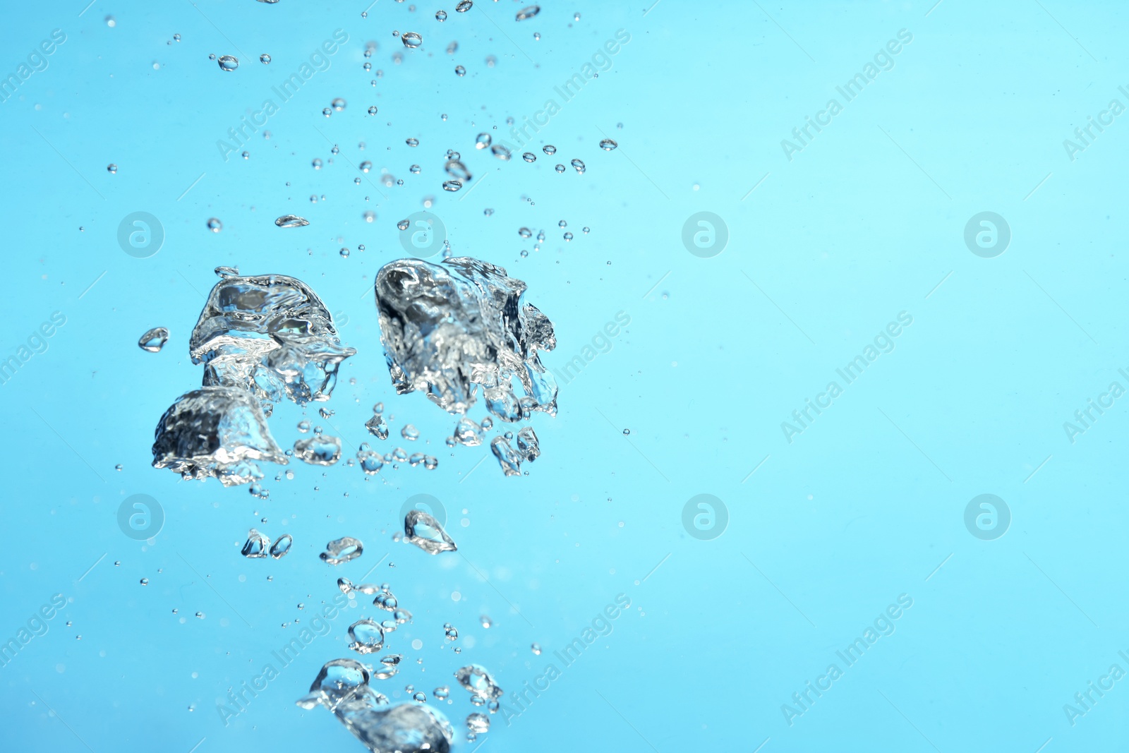 Photo of Air bubbles in water on light blue background. Space for text