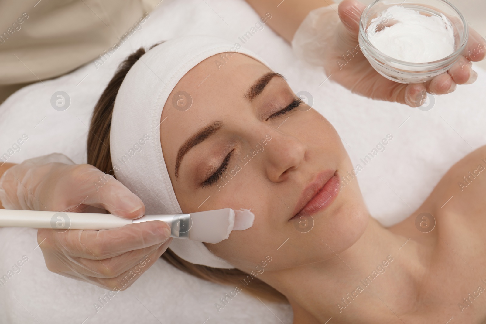 Photo of Young woman during face peeling procedure in salon