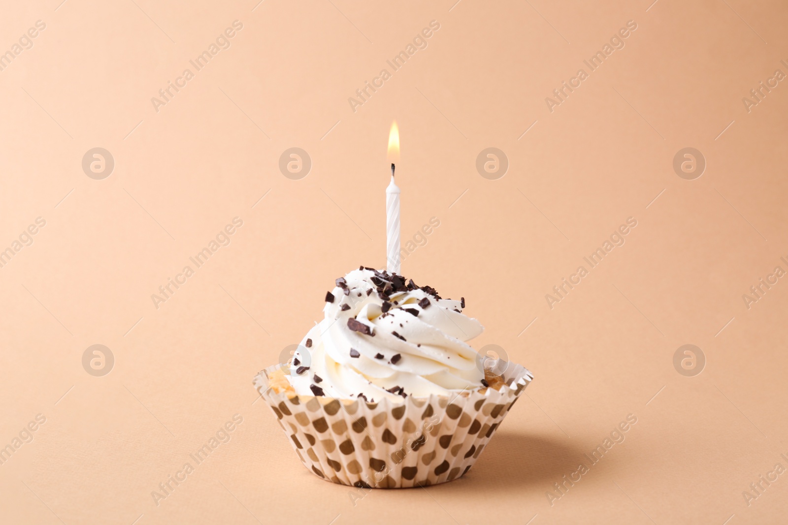Photo of Delicious birthday cupcake with candle on beige background