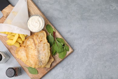 Delicious fish and chips with tasty sauce, mangold and spices on gray table, top view. Space for text