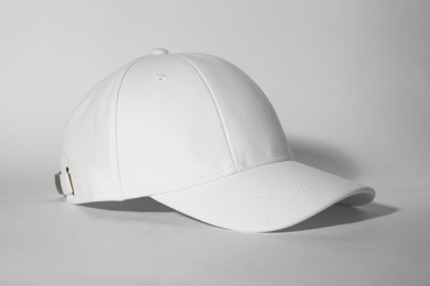 Photo of Stylish white baseball cap on light background