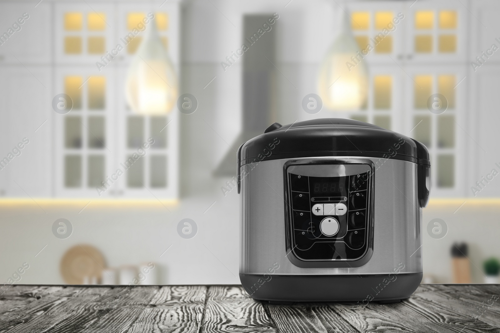 Image of Modern electric multi cooker on wooden table in kitchen. Space for design