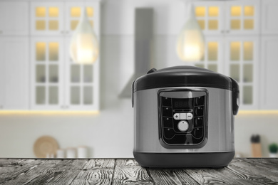 Image of Modern electric multi cooker on wooden table in kitchen. Space for design