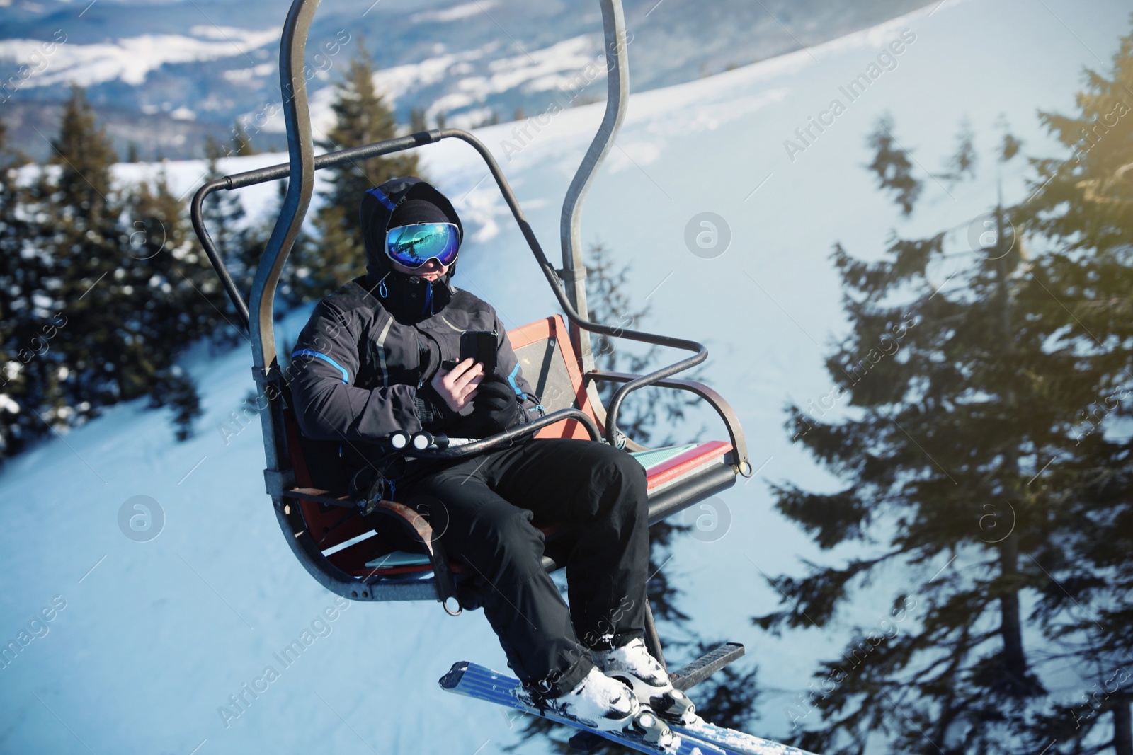 Photo of Man using chairlift at mountain ski resort. Winter vacation