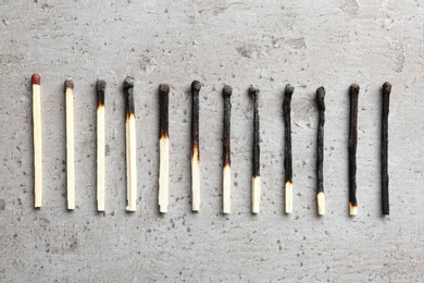Row of burnt matches and whole one on grey background, flat lay. Human life phases concept