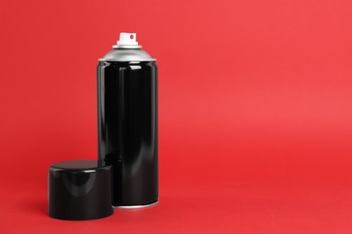 Photo of Black can of spray paint on red background. Space for text