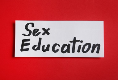 Photo of Piece of paper with phrase "SEX EDUCATION" on red background, top view