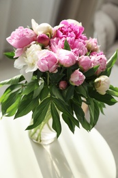 Photo of Vase with bouquet of beautiful peonies on table in room, above view