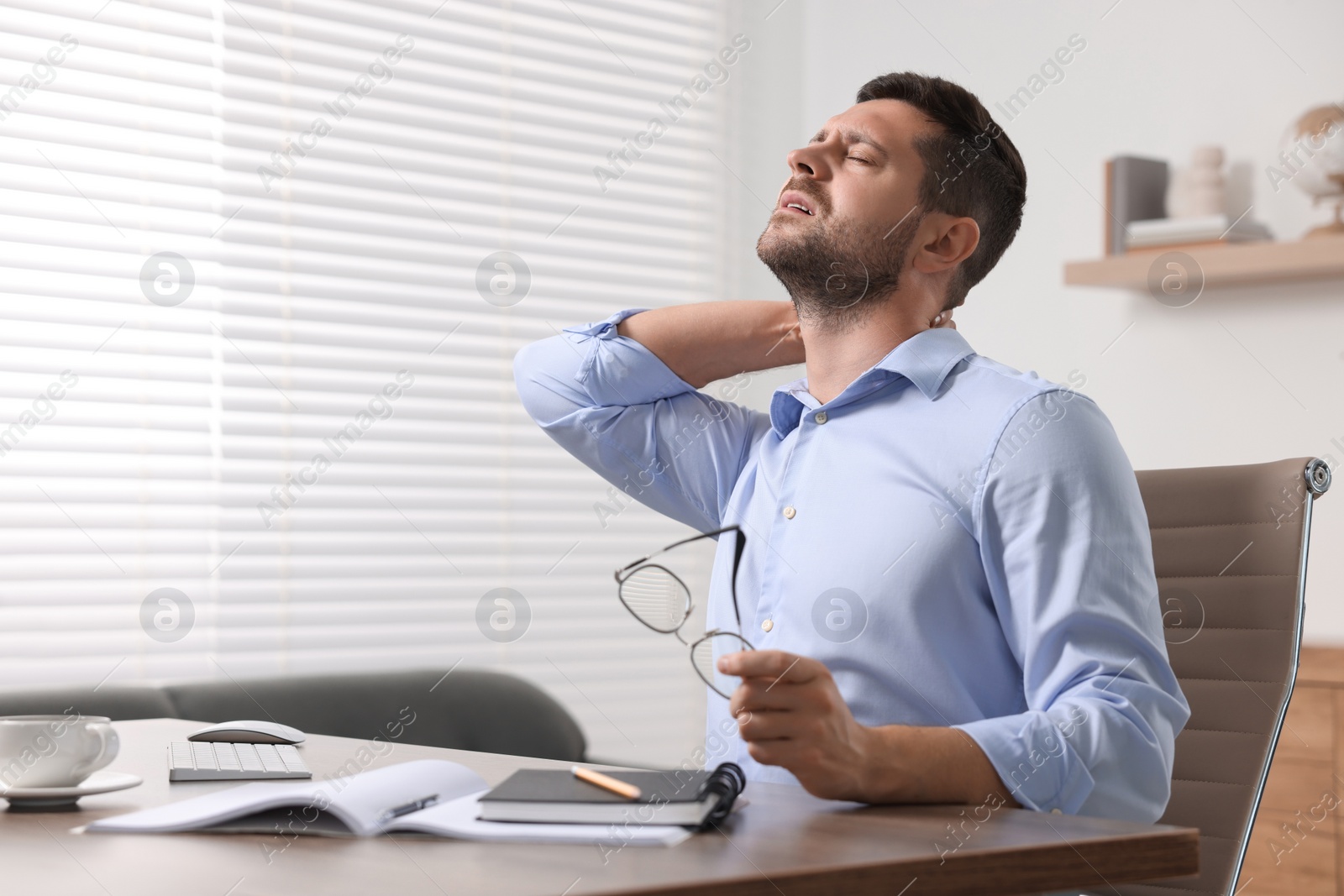 Photo of Man suffering from neck pain in office