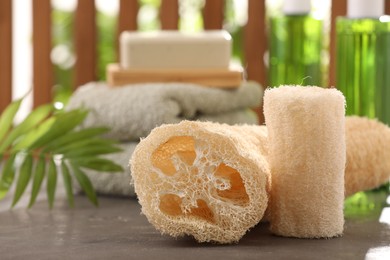 Photo of Natural loofah sponges on grey textured table