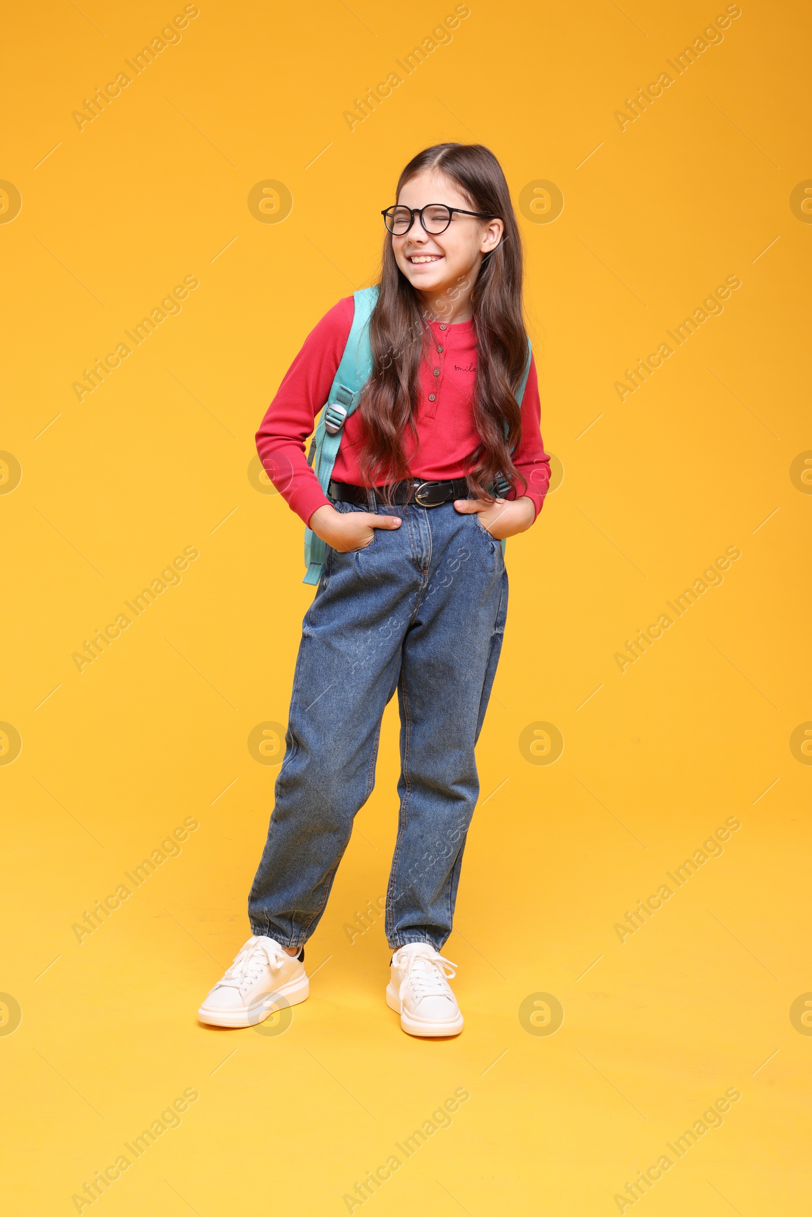 Photo of Cute schoolgirl in glasses on orange background