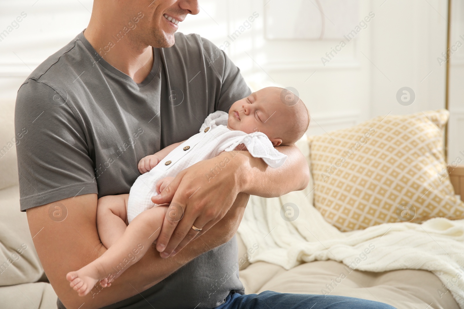 Photo of Father holding his sleeping baby at home, closeup