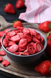 Photo of Freeze dried and fresh strawberries on wooden board, closeup