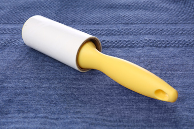 New lint roller with yellow handle on blue fabric