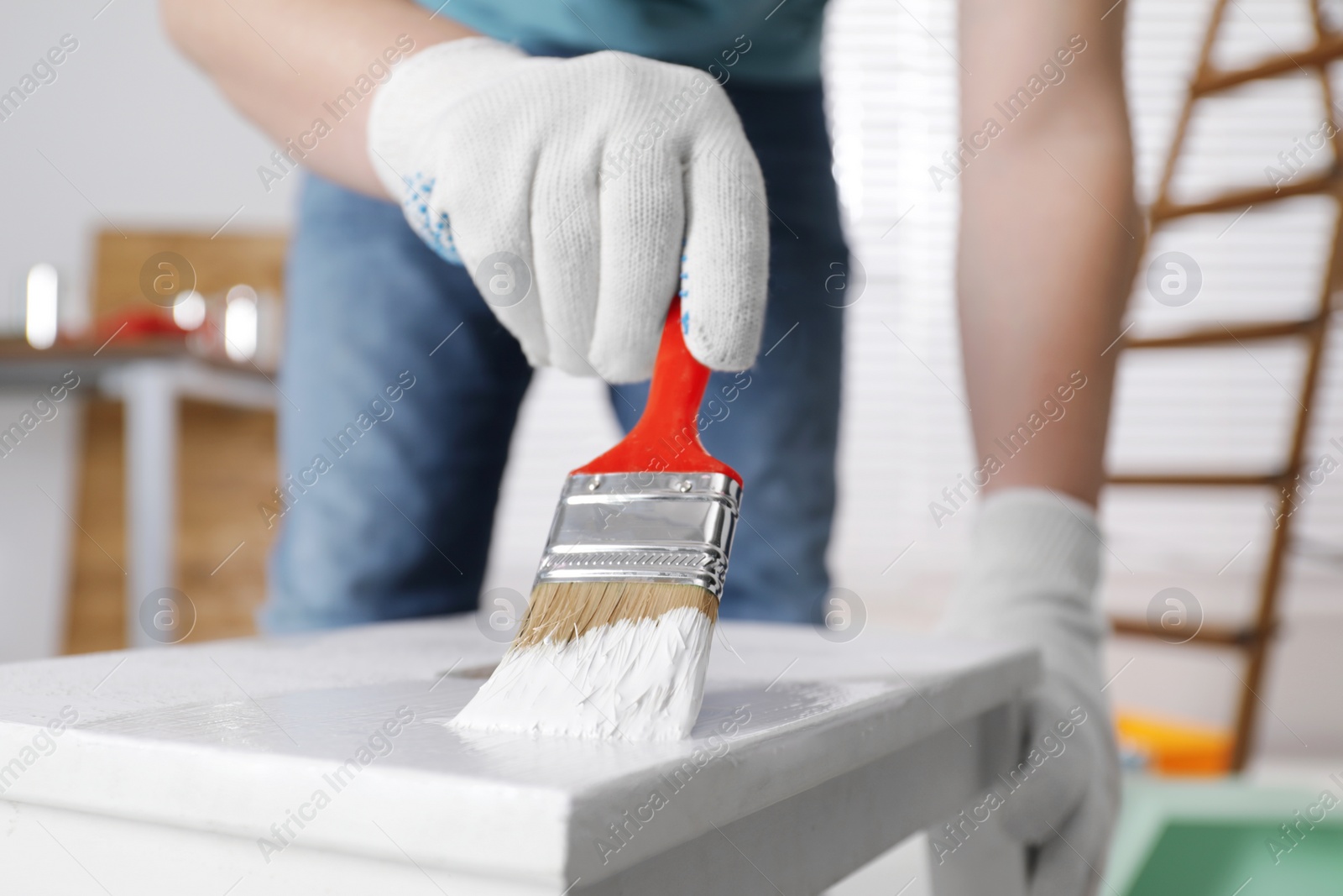 Photo of Man using brush to paint bekvam with white dye indoors, closeup