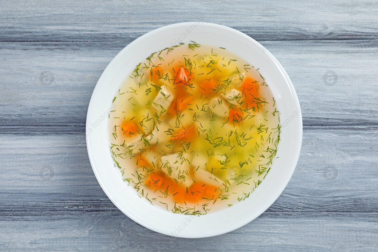 Photo of Bowl of fresh homemade soup to cure flu on wooden background, top view