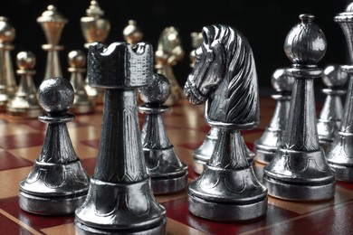 Photo of Chessboard with game pieces on black background, closeup