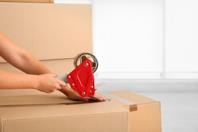 Woman packing carton box indoors, closeup. Moving day