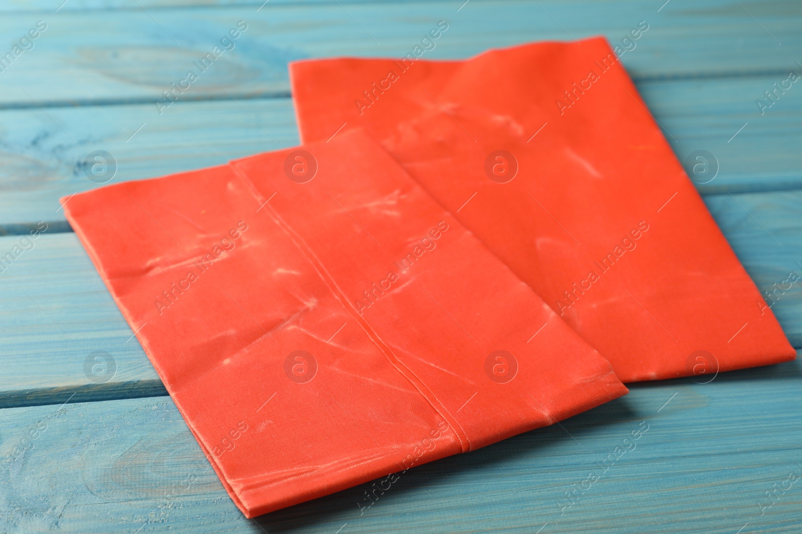 Photo of Red reusable beeswax food wraps on light blue wooden table, closeup