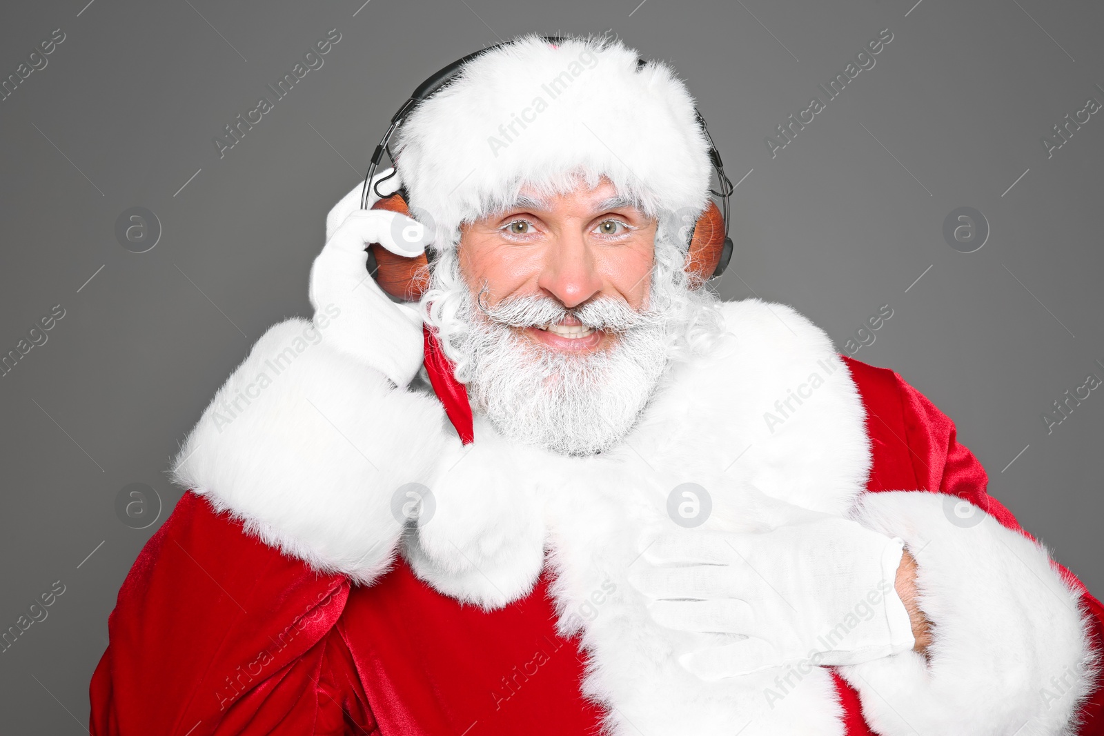 Photo of Santa Claus listening to Christmas music on color background