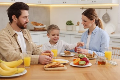 Happy family having breakfast at table in kitchen