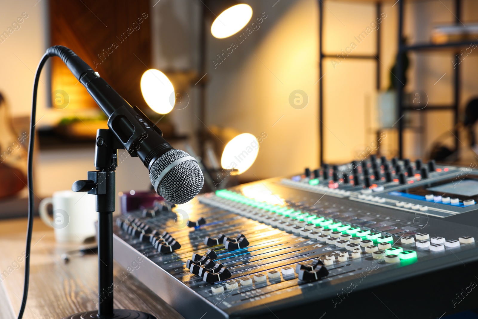 Photo of Microphone and professional mixing console on table in radio studio