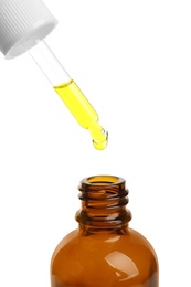Photo of Pipette with oil over bottle on white background