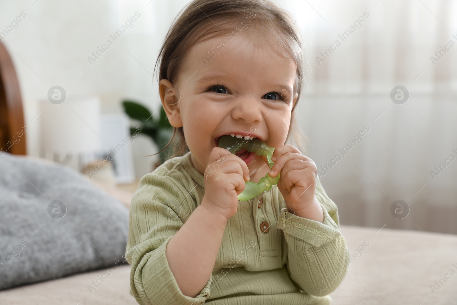 Photo of Cute baby girl with teething toy at home