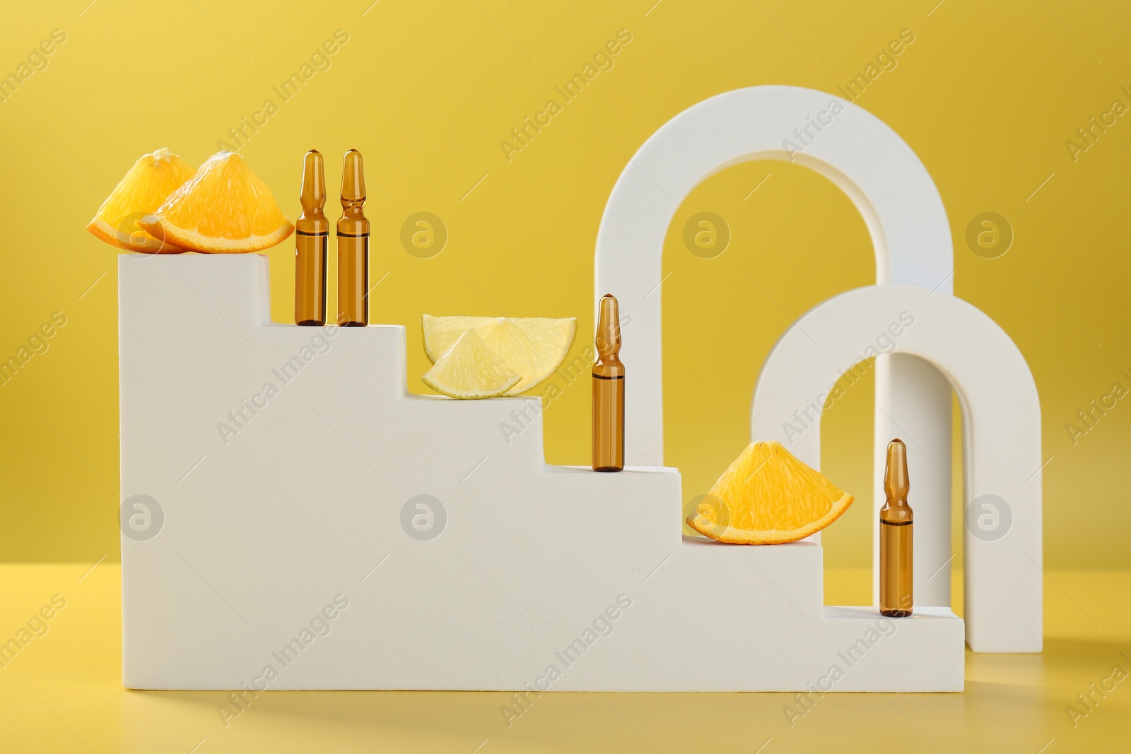 Photo of Stylish presentation of skincare ampoules with vitamin C and citrus slices on yellow background