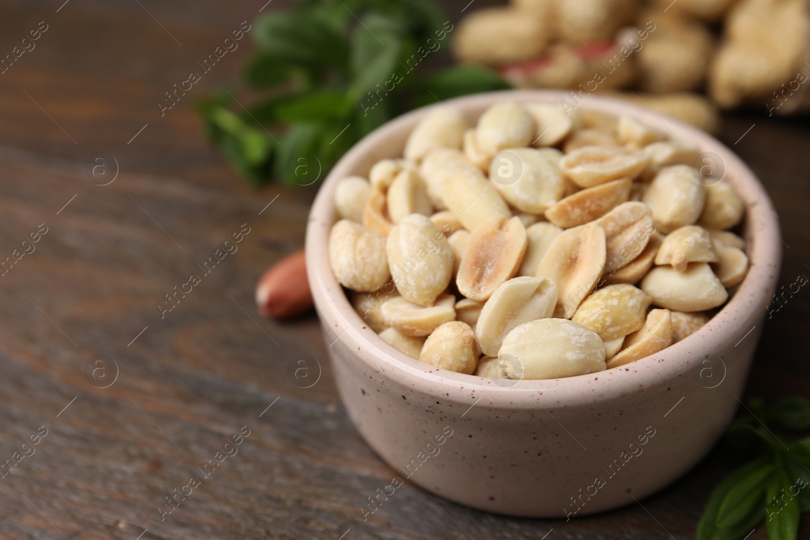 Photo of Fresh peeled peanuts in bowl on wooden table, closeup. Space for text