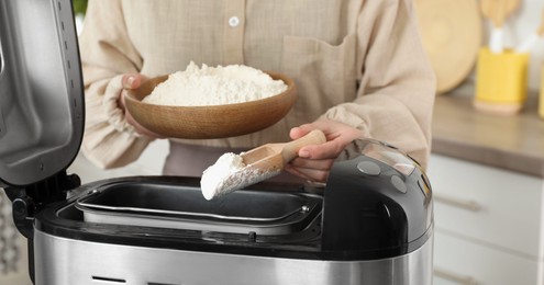 Photo of Making dough. Woman adding flour into breadmaker machine, closeup