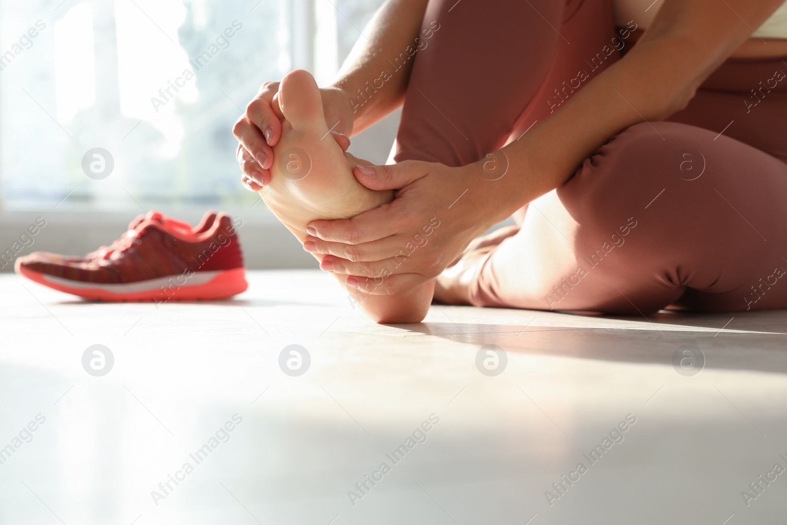 Photo of Woman suffering from foot pain indoors, closeup