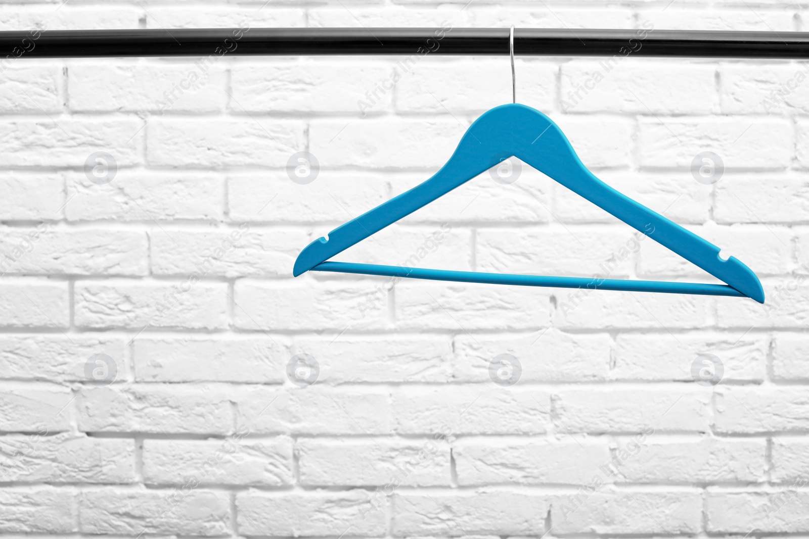 Photo of Clothes hanger on metal rail against brick wall background