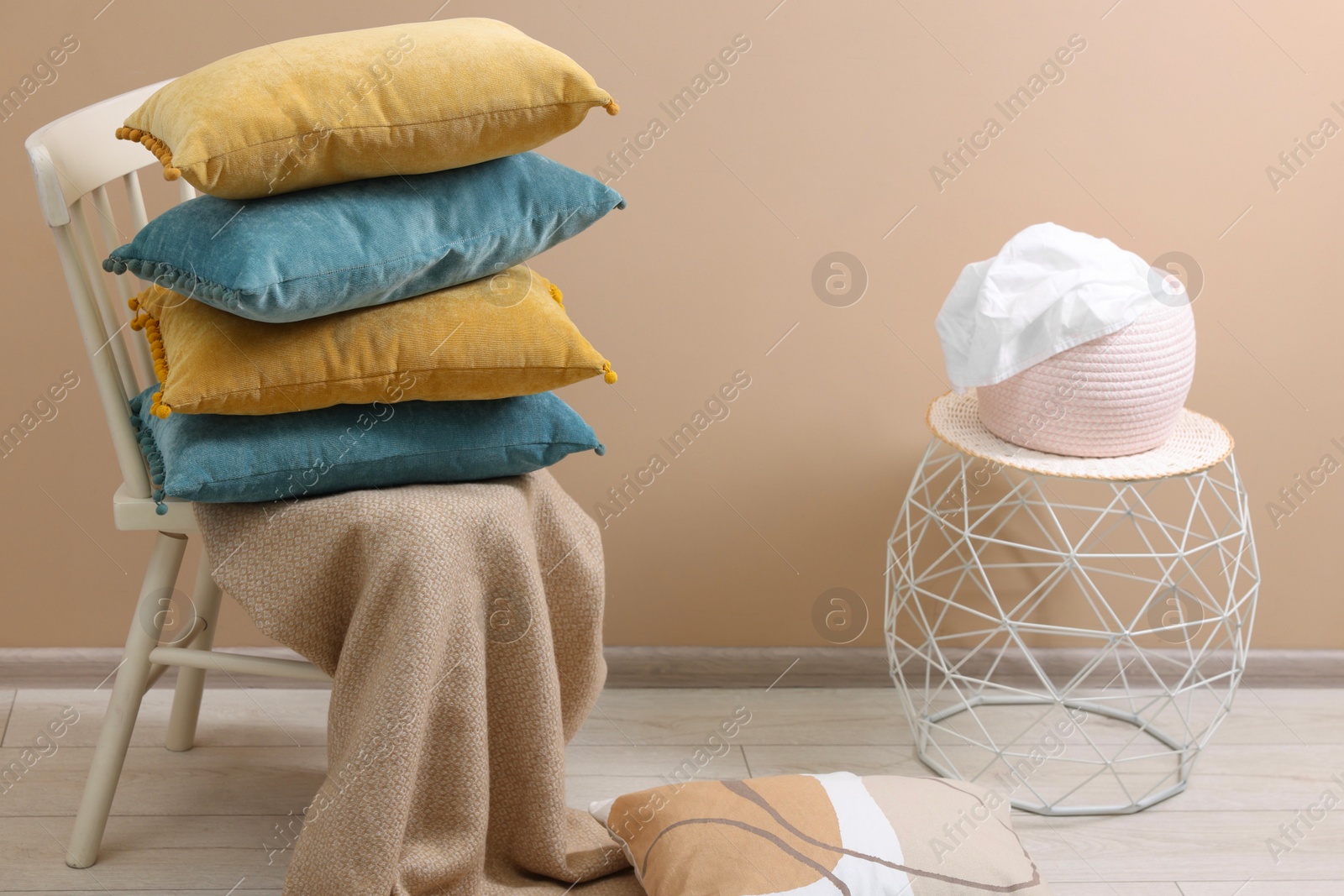 Photo of Soft pillows and warm blanket near beige wall indoors