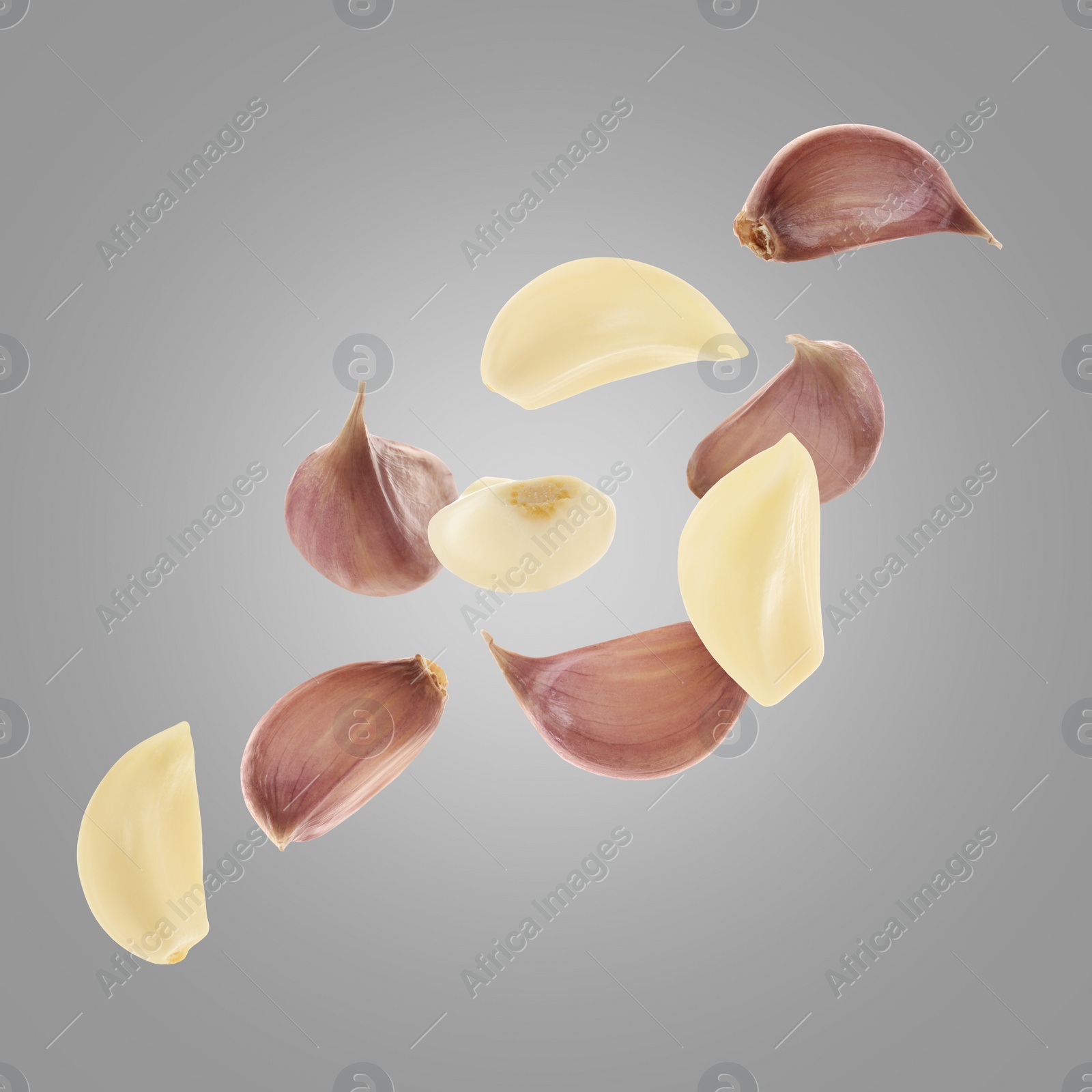 Image of Fresh garlic cloves falling on grey background