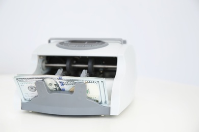 Photo of Counting machine with money on white table. Space for text