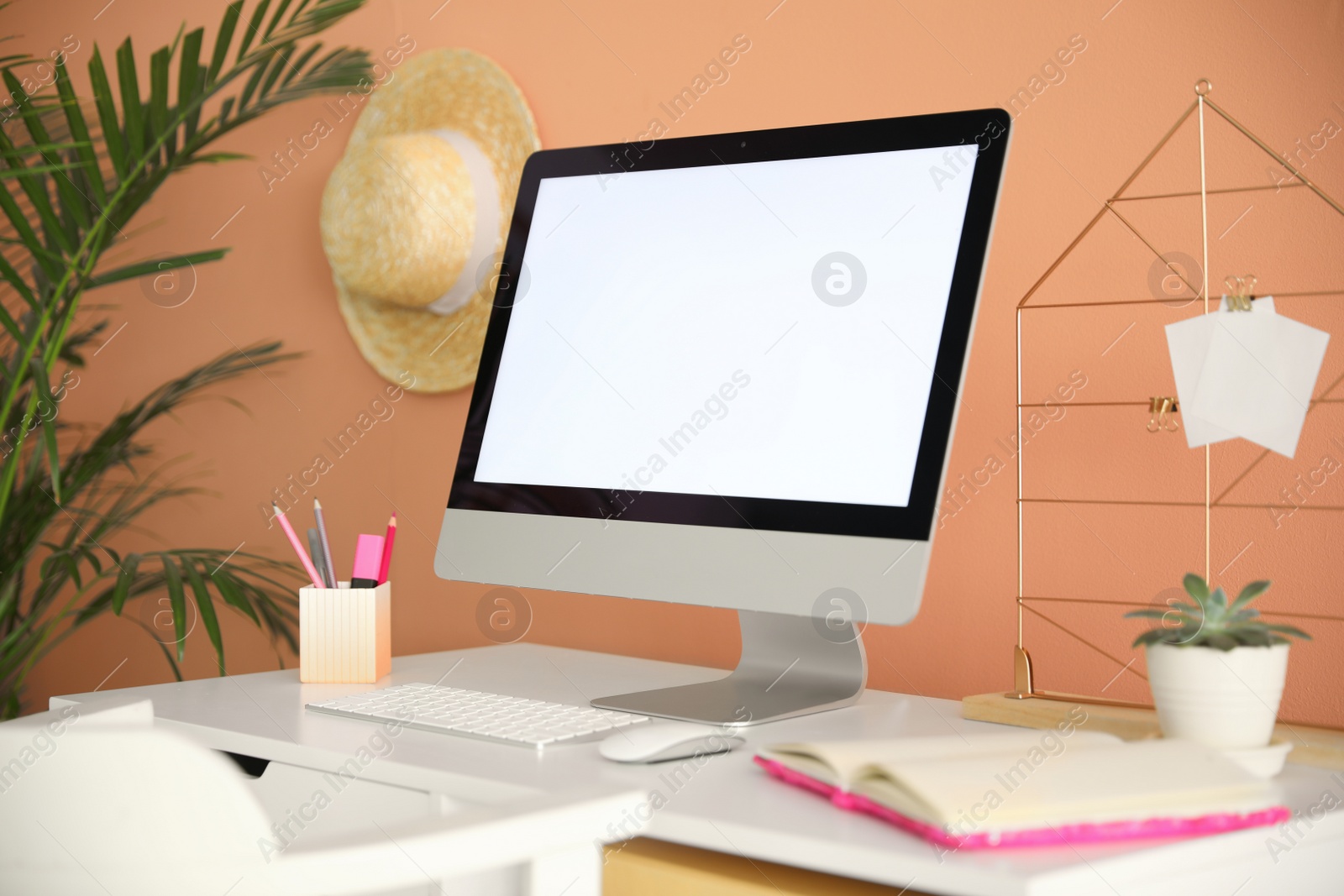 Photo of Comfortable workplace with modern computer on table near orange wall. Space for design